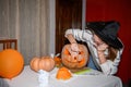 A girl carving big orange pumpkin into jack-o-lantern for Halloween holiday decoration at kitchen. Decoration for party Royalty Free Stock Photo