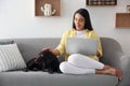 Young woman with eye patches working on laptop near her dog in living room. Home office concept Royalty Free Stock Photo