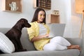 Young woman with eye patches working on laptop near her dog in living room. Home office concept Royalty Free Stock Photo