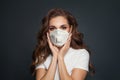 Young woman in face mask on dark gray background. Woman in medical mask portrait
