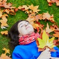 Young woman on a fall day, laying on the ground with colorful autumn leaves Royalty Free Stock Photo