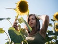 Young woman farmer posing with a harvest of large huge sunflowers in field