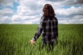 Young woman farmer walks at the green wheat field touching spikelets with her hand. Female farm worker checking the Royalty Free Stock Photo