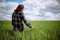 Young woman farmer walks at the green wheat field touching spikelets with her hand. Female farm worker checking the Royalty Free Stock Photo