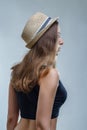 Young woman in fashionable hat and black shirt posing in a half turn from the back on gray background in studio Royalty Free Stock Photo