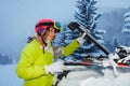 Young woman fastening skis on the roof of car