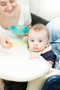 Young woman feeding her baby from spoon with apple sauce Royalty Free Stock Photo