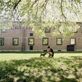 Young woman feeding her dog and let him drink water outdoors in the park. Shot on analog medium format film Royalty Free Stock Photo