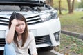 Young woman sitting near the broken down car