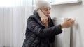 Young woman feeling cold at home calling repairman to fix broken heating radiator. Concept of energy crisis, high bills, broken Royalty Free Stock Photo