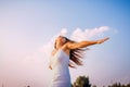Young woman feeling free and happy raising arms and spinning around outdoors at sunset