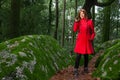 Young woman feeling sad walking alone on forest path wearing red long coat Royalty Free Stock Photo