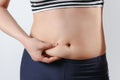Young woman feels hand folds on her stomach. On light background. Concept of weight loss, proper nutrition, excess weight, women` Royalty Free Stock Photo