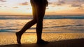 Young woman feet walking barefoot on beach by sea at golden sunset leaving footprints in sand. Female tourist enjoy Royalty Free Stock Photo