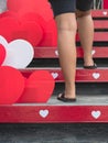 Young woman feet walking up stairs with beautiful red and white heart shape made from corrugated plastic sheets decorate on the