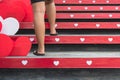 Young woman feet walking up stairs with beautiful red and white heart shape made from corrugated plastic sheets decoration on