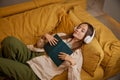 Young woman fell asleep while reading book and listening music in headphones Royalty Free Stock Photo