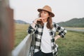 Young woman in felt hat and plaid shirt near old wooden fence on the mountains background Royalty Free Stock Photo