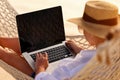 Young woman female freelancer using laptop while lying in hammock on the tropical beach at sunset Royalty Free Stock Photo