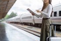 Young woman female traveler looking on map while waiting for the train at train station Royalty Free Stock Photo