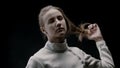 A young woman fencer lets her hair down and shakes her head up and down