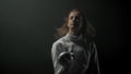 A young woman fencer with long hair playing with her sword in the dark studio