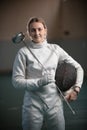 A young woman fencer with a ponytail standing in the school gym