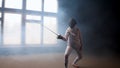 A young woman fencer showing basic attack movements on the fencing