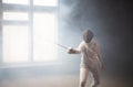 A young woman fencer standing in the attack position