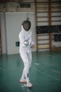 A young woman fencer standing in the fight pose holding a sword