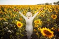 Young woman in a field of sunflowers stands back and looks at the sunset feeling freedom and joy. Female wearing a hat Royalty Free Stock Photo