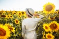 Young woman in a field of sunflowers stands back and looks at the sunset feeling freedom and joy. Female wearing a white Royalty Free Stock Photo