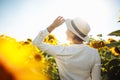 Young woman in a field of sunflowers stands back and looks at the sunset feeling freedom and joy. Female wearing a white dress Royalty Free Stock Photo