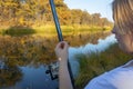 Young woman fisherman with fishing rod holds a hook with bait for fishing