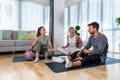 Young woman fitness and yoga instructor helping couple in their home for workout exercises. Female coach working with clients