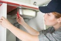 young woman fixes plumbing under kitchen sink Royalty Free Stock Photo