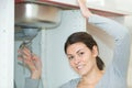 young woman fixing sink pipe with adjustable wrench in kitchen Royalty Free Stock Photo