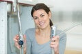 Young woman fixing sink pipe with adjustable wrench in kitchen Royalty Free Stock Photo