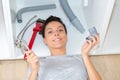 young woman fixing sink pipe with adjustable wrench in kitchen Royalty Free Stock Photo