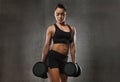 Young woman flexing muscles with dumbbells in gym Royalty Free Stock Photo