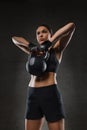 Young woman flexing muscles with kettlebell in gym