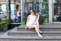 Young woman on the floor on the street looking in camera using p Royalty Free Stock Photo