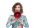 Young woman in floral dress emotionally shouts into a red megaphone, isolated on white background.