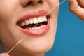 Young woman flossing her teeth on blue background, closeup. Cosmetic dentistry Royalty Free Stock Photo