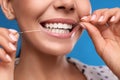 Young woman flossing her teeth on blue background, closeup. Cosmetic dentistry Royalty Free Stock Photo