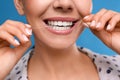 Young woman flossing her teeth on blue background, closeup. Cosmetic dentistry Royalty Free Stock Photo