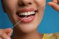 Young woman flossing her teeth on blue background, closeup. Cosmetic dentistry Royalty Free Stock Photo