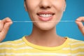 Young woman flossing her teeth on blue background, closeup. Cosmetic dentistry Royalty Free Stock Photo