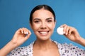 Young woman flossing her teeth on blue background. Cosmetic dentistry Royalty Free Stock Photo