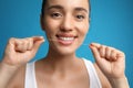 Young woman flossing her teeth on blue background. Cosmetic dentistry Royalty Free Stock Photo